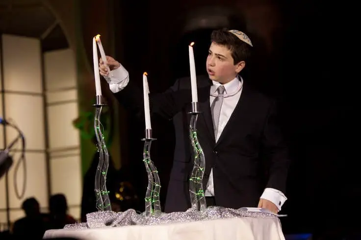 jewish boy lighting three candles at bar mitzvah lighting ceremony