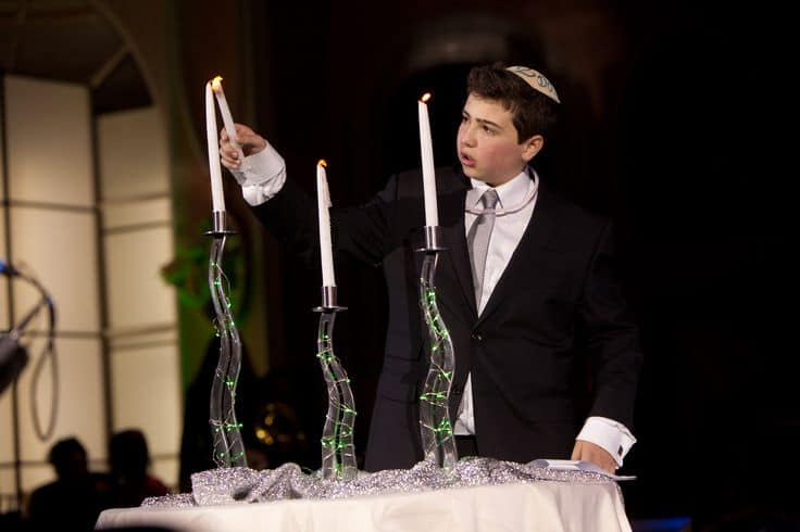 jewish boy lighting three candles at bar mitzvah candle lighting ceremony